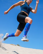 Woman running on sand with compressions socks.