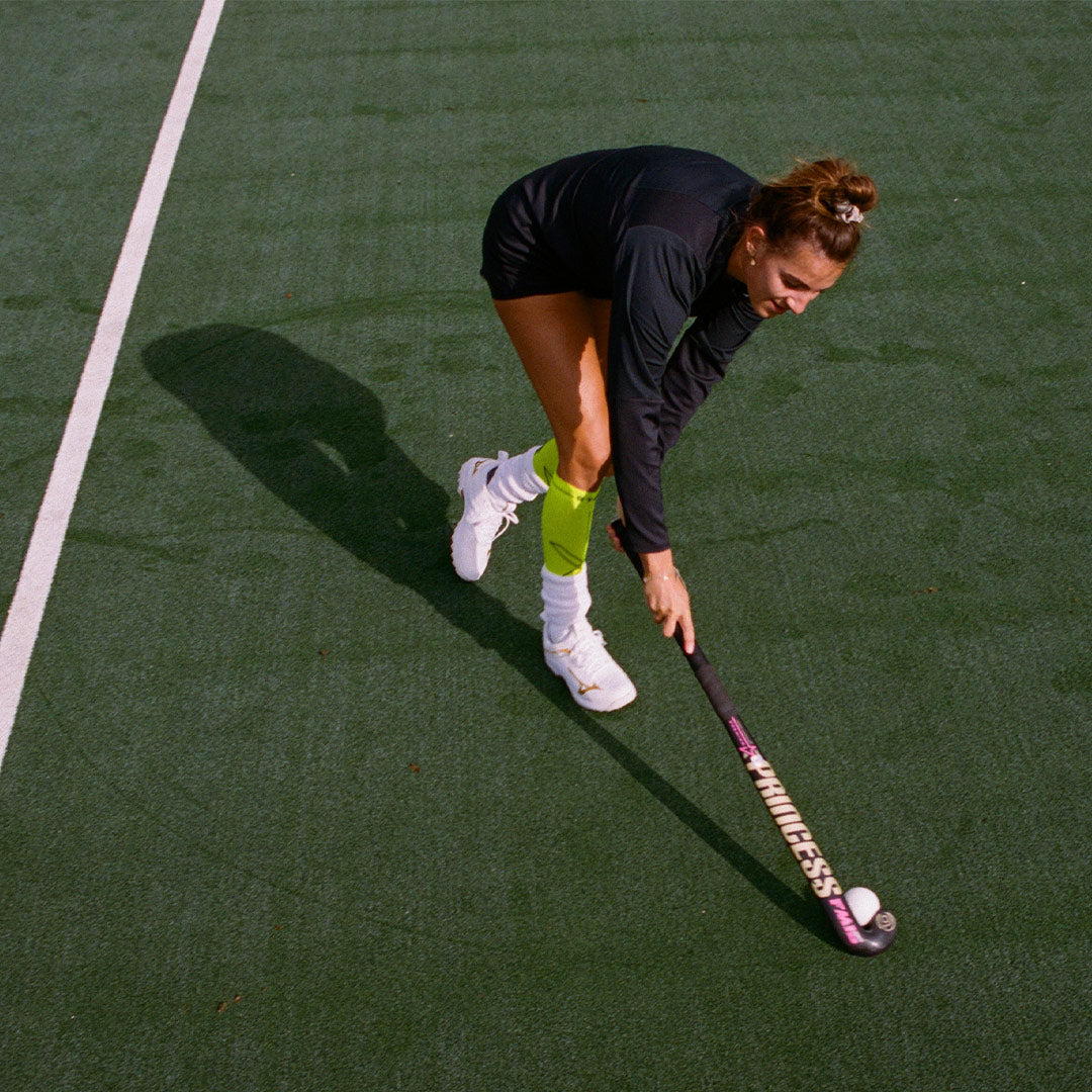 Field hockey player on field in action seen from above.