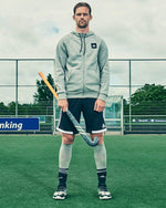 Mirco Pruyser standing in front of a goal while holding a hockey stick.