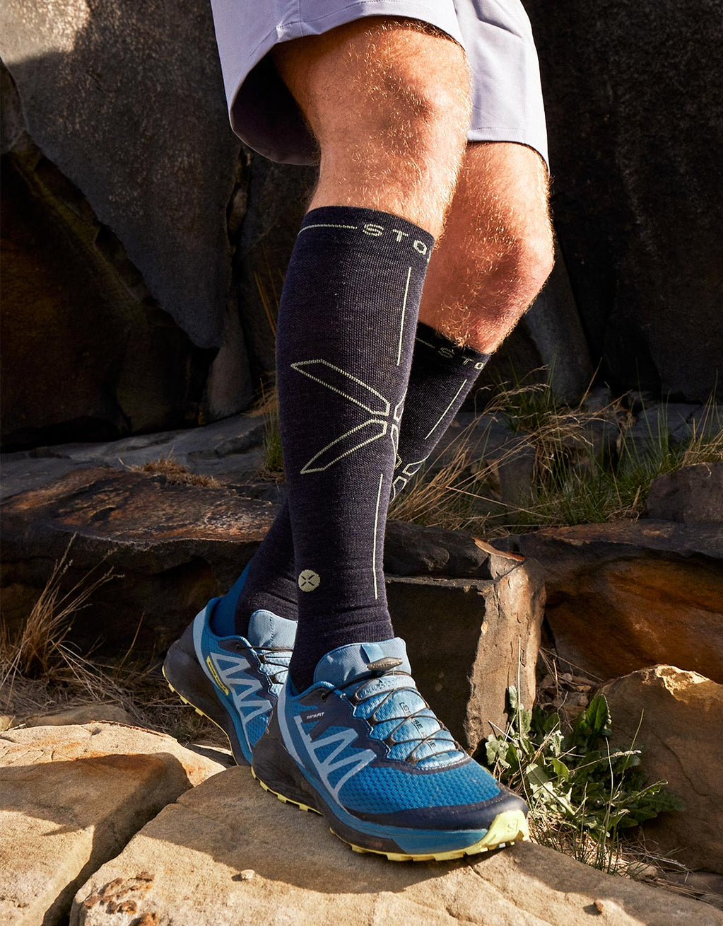 Man is walking across rocks in the sun.