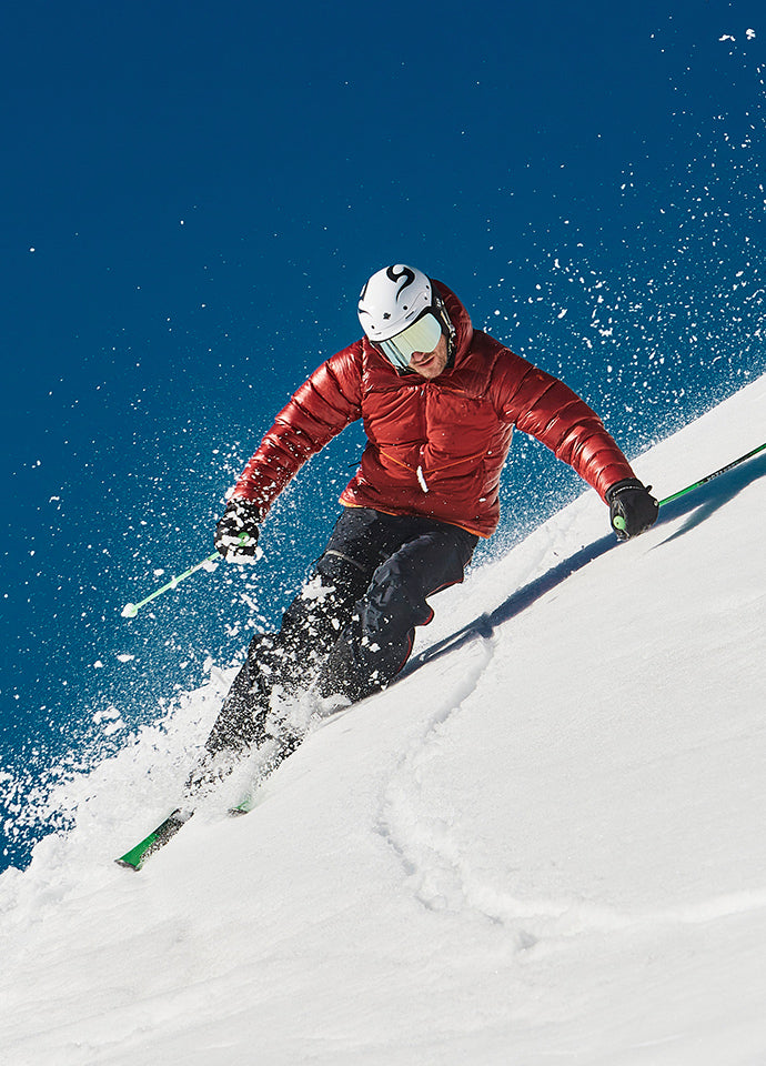 Man skiing down a mountain whilst wearing a red jacket.  - 