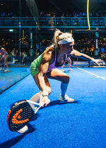 Person bending down with a racket in her hands. -