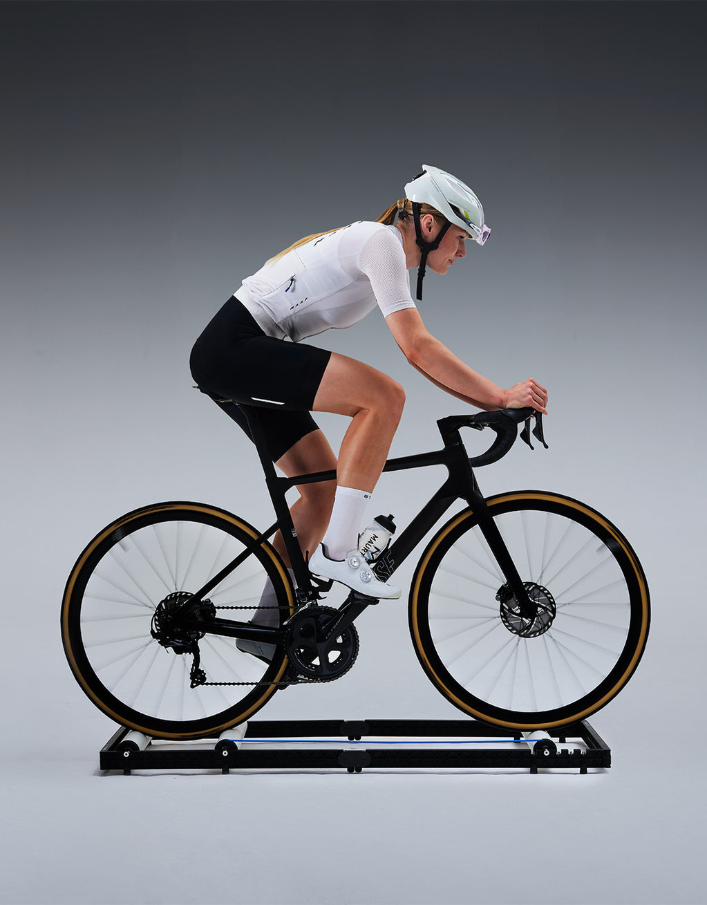 A cyclist on a bike in a grey studio.