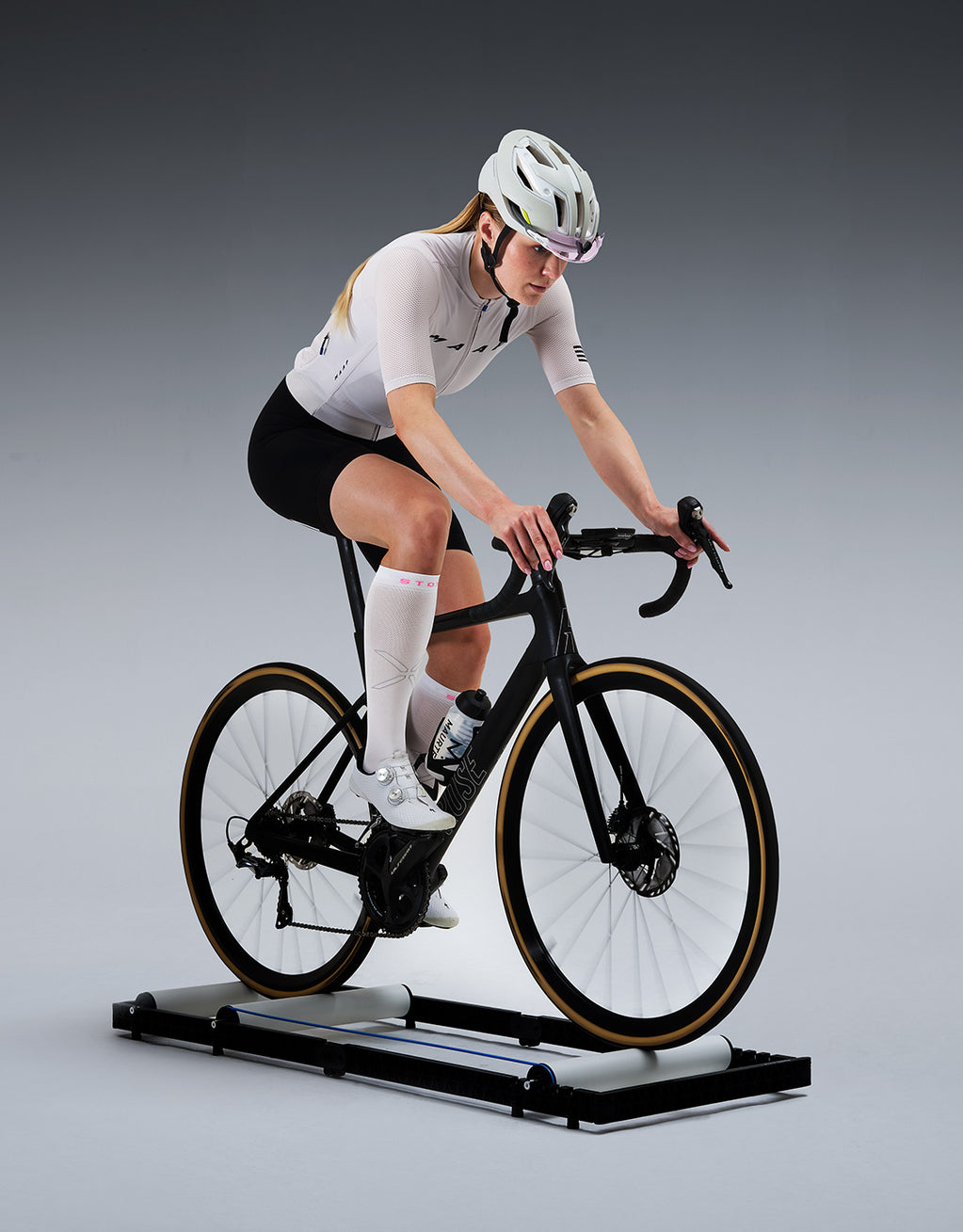A cyclist on a bike in a grey studio.
