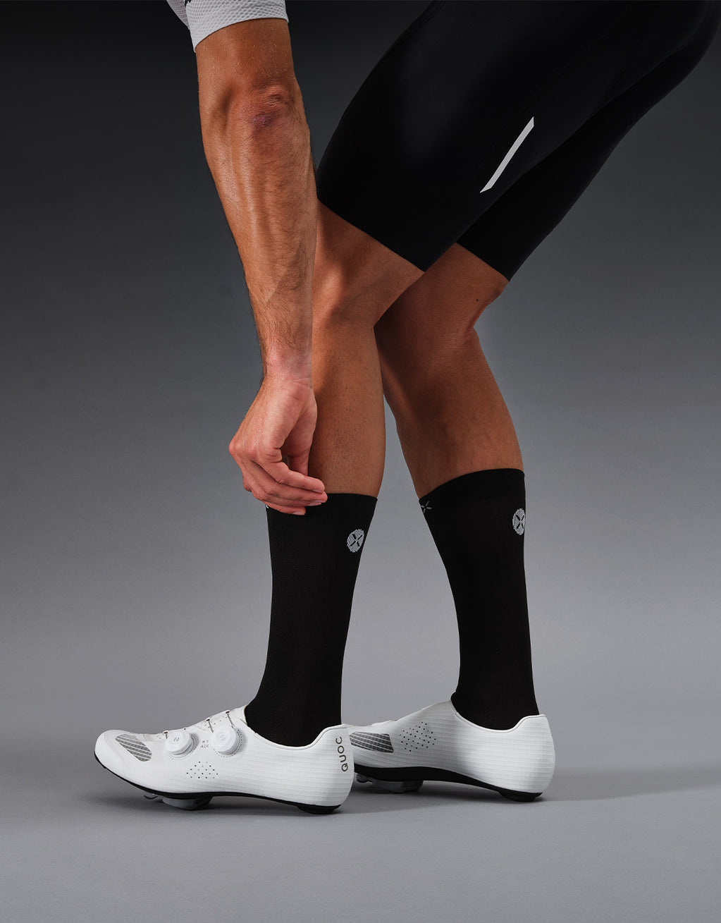 A cyclist with balck socks on in a grey studio.