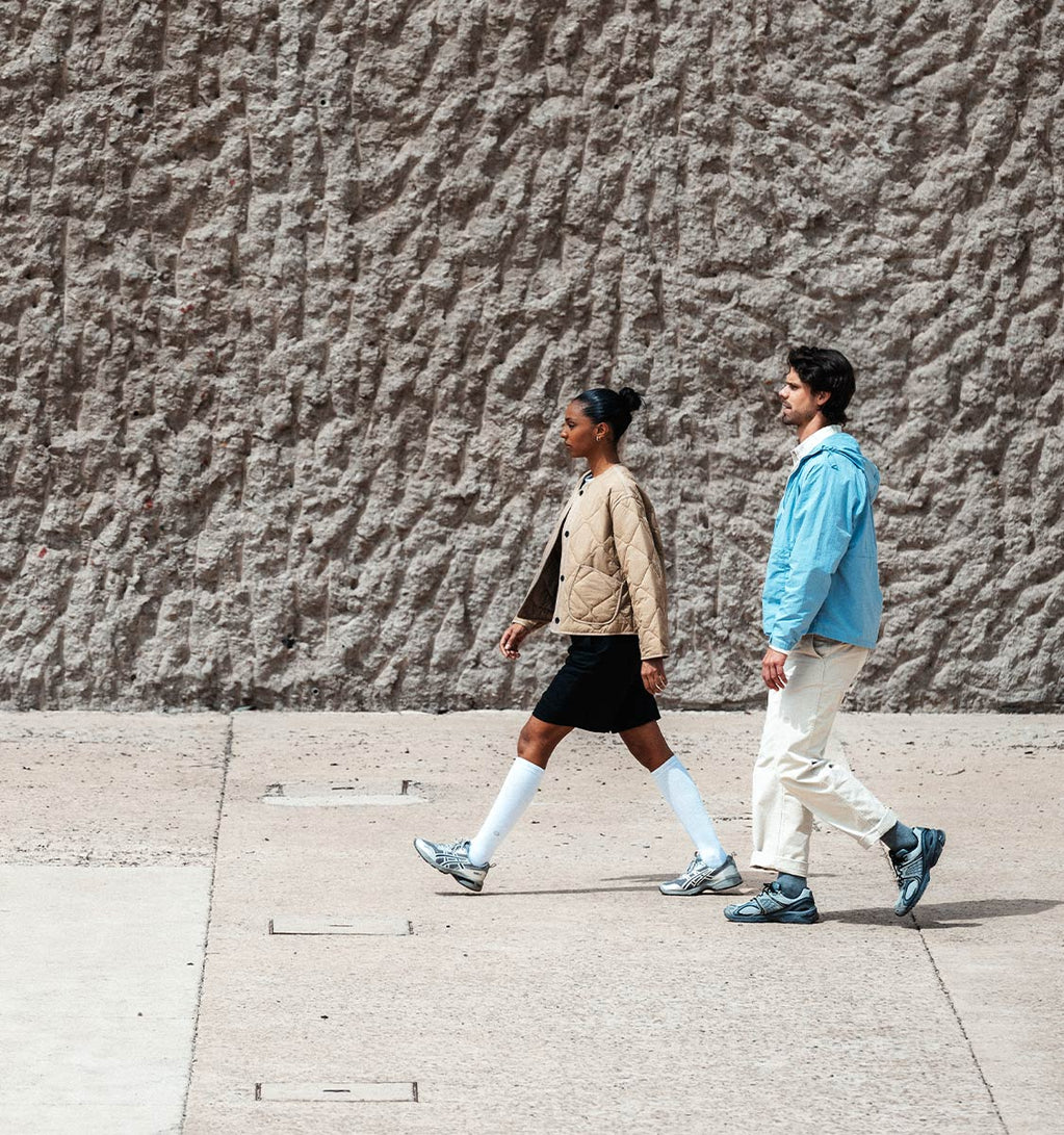 Couple walking in front of a wall.