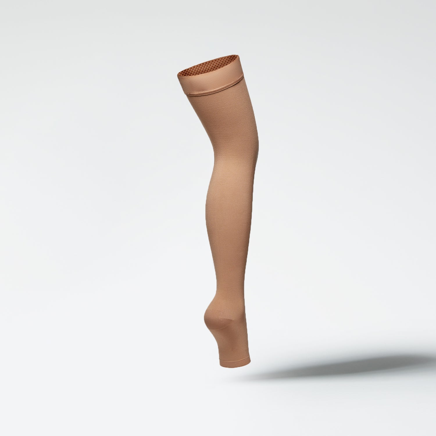 Side view of a medical thigh high stocking in sand.