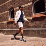 Man walking across brick stone street in the sun.