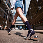 Two female legs with buildings in the background.