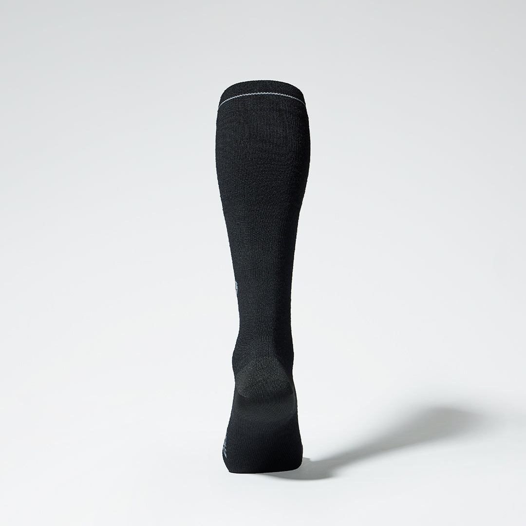 Black knee high compression sock with grey details seen from the back.