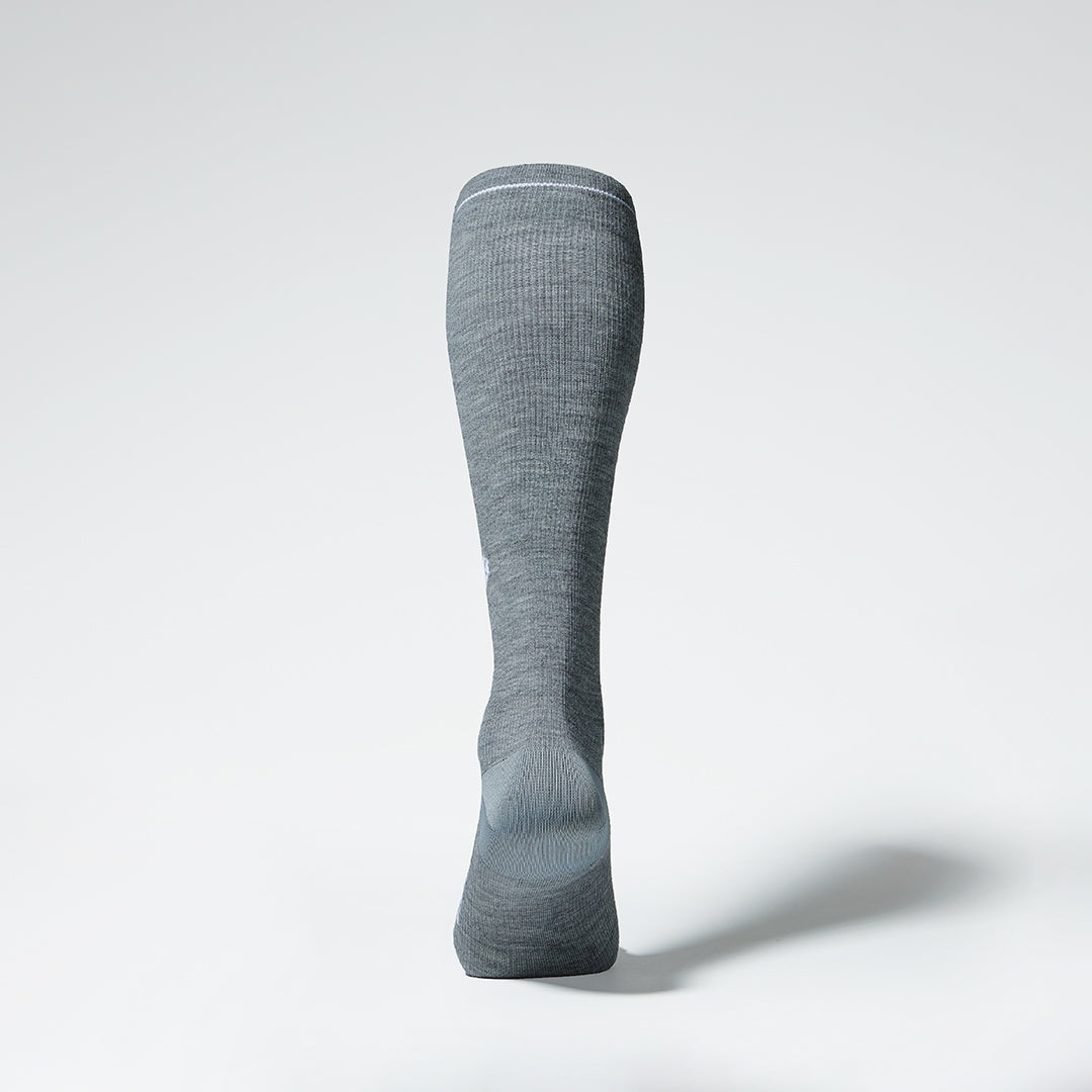 Back view of a grey knee high compression sock with white details.