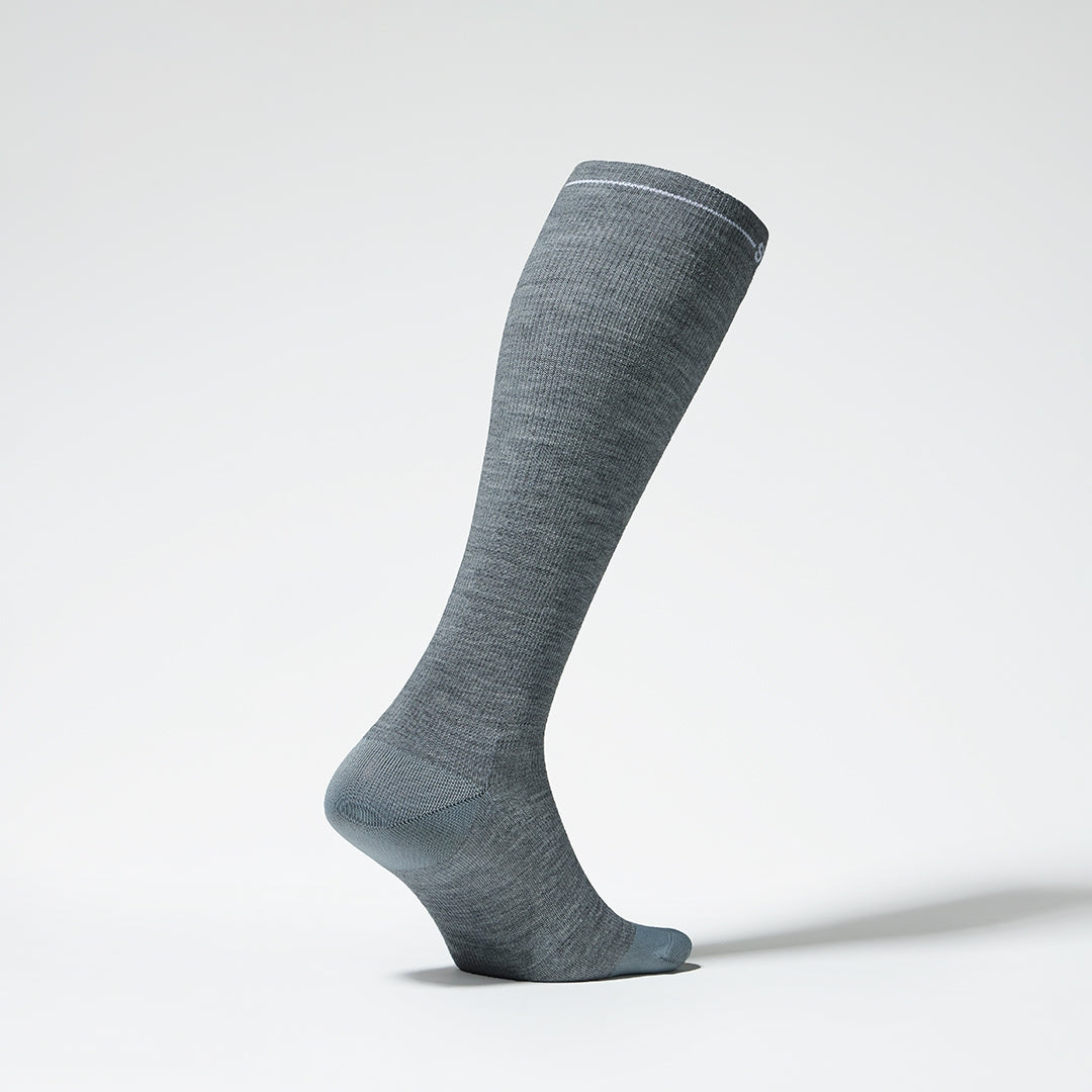 Side view of a grey knee high compression sock with white details.