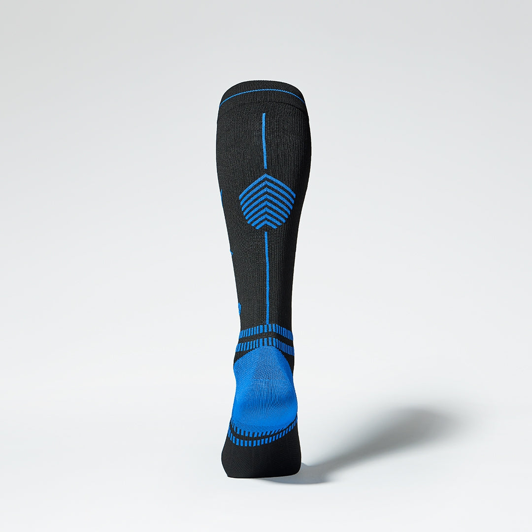 Back view of a black knee high compression sock with blue details.