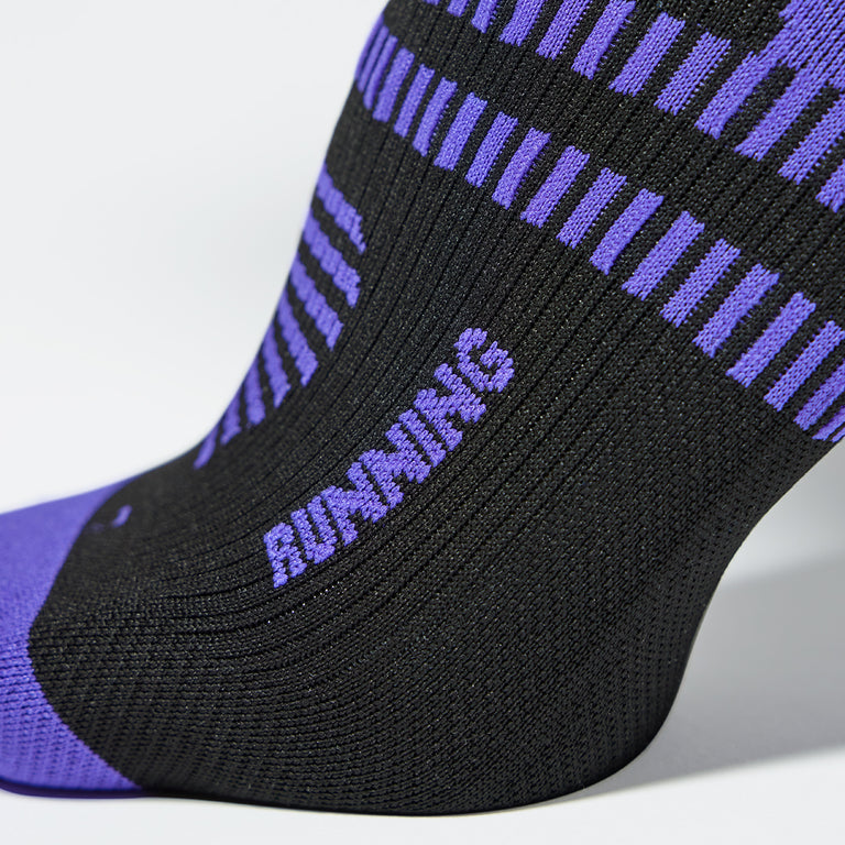 Close up of a black colored compression sock with a purple logo. 