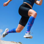 Legs of a woman running on the beach wearing blue knee high compression socks with pink details.