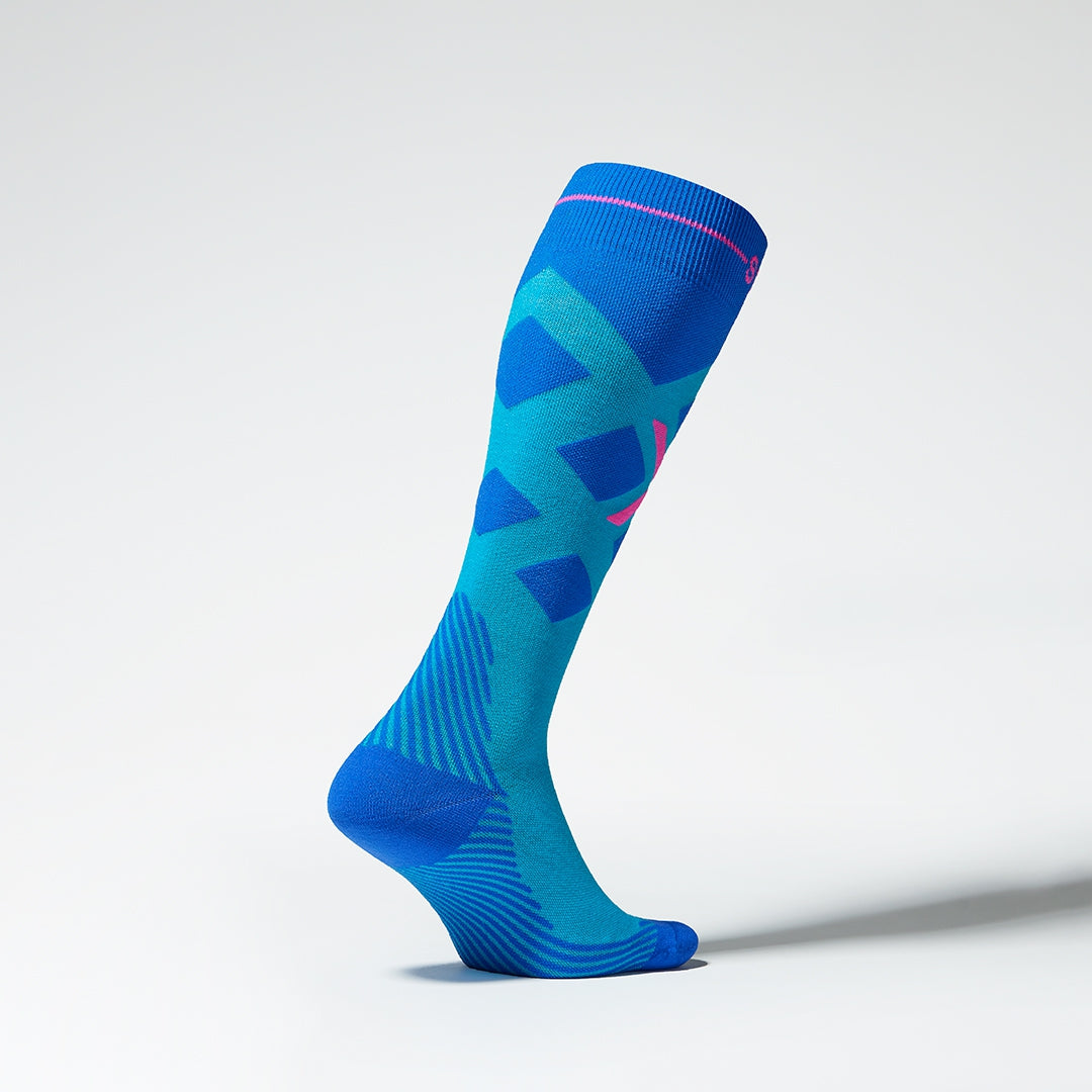 Side view of a turquoise compression skiing socks with pink details.