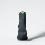 View of the back of an ankle high compression sock in dark grey with green accents.