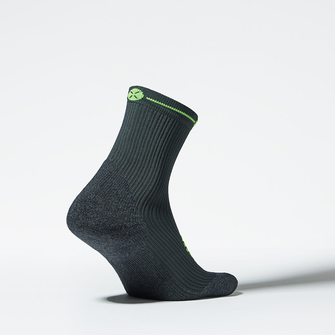 Side view of a compression sock in dark grey with green accents. 