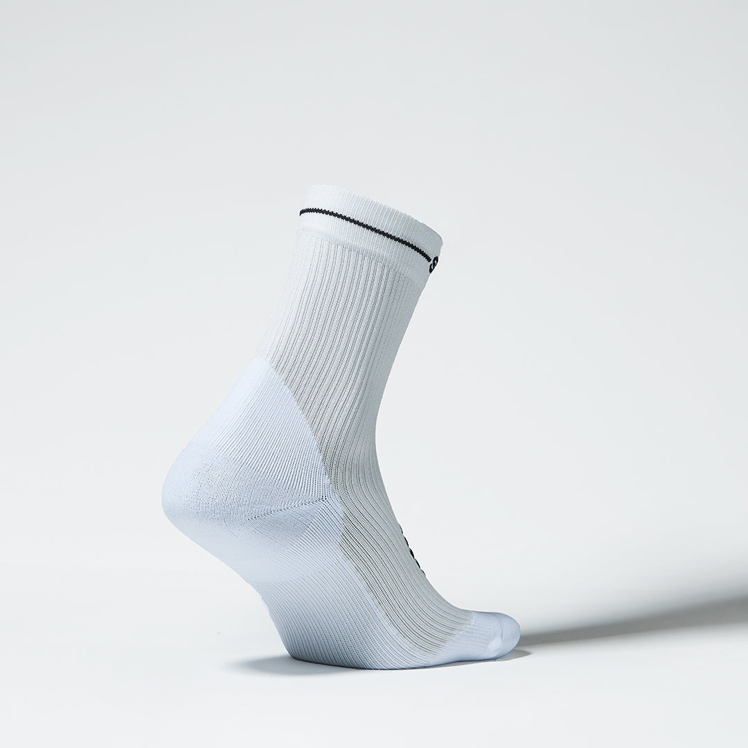 View of the side of an ankle high compression sock in white with black details. 