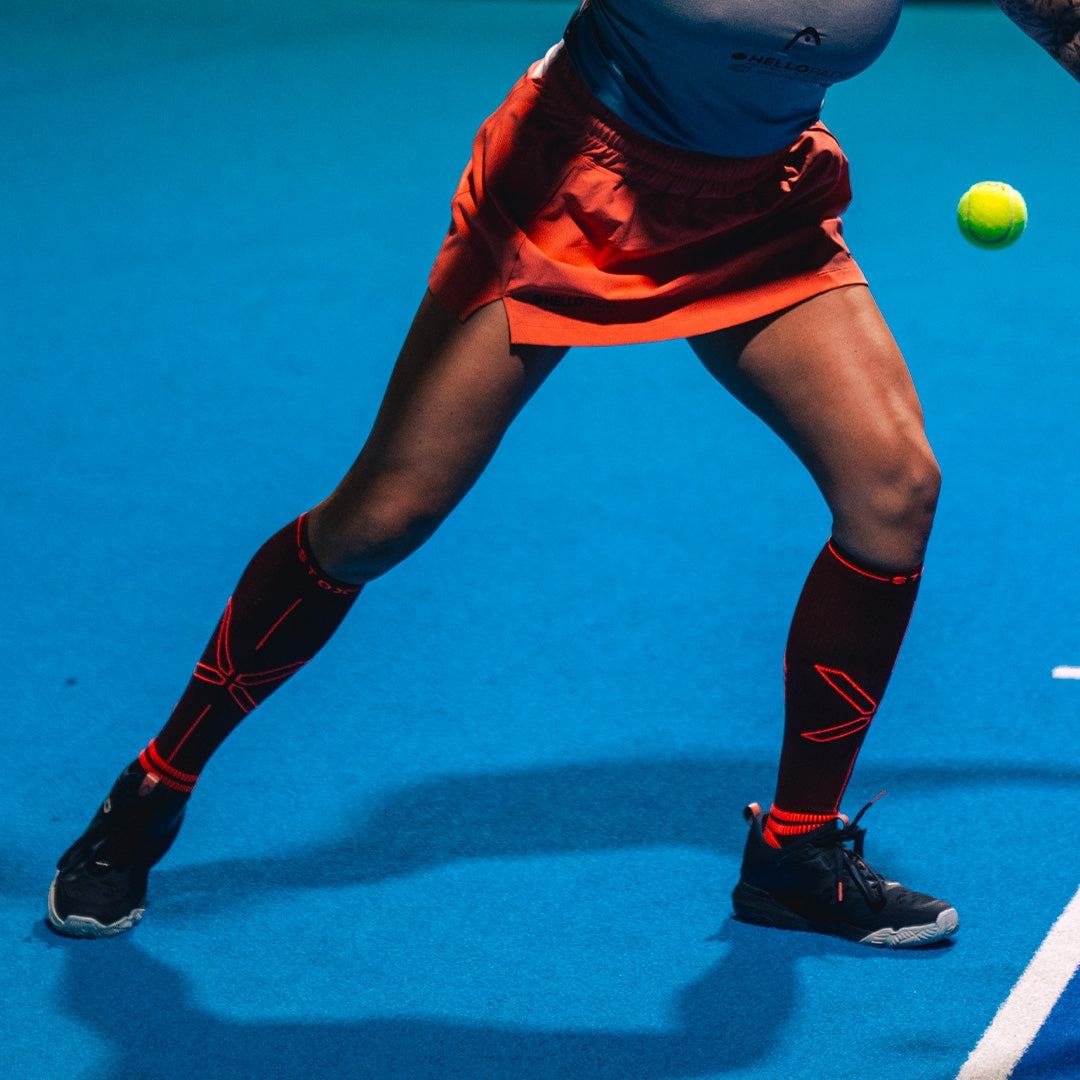 Woman legs playing padel tennis on a blue court. 