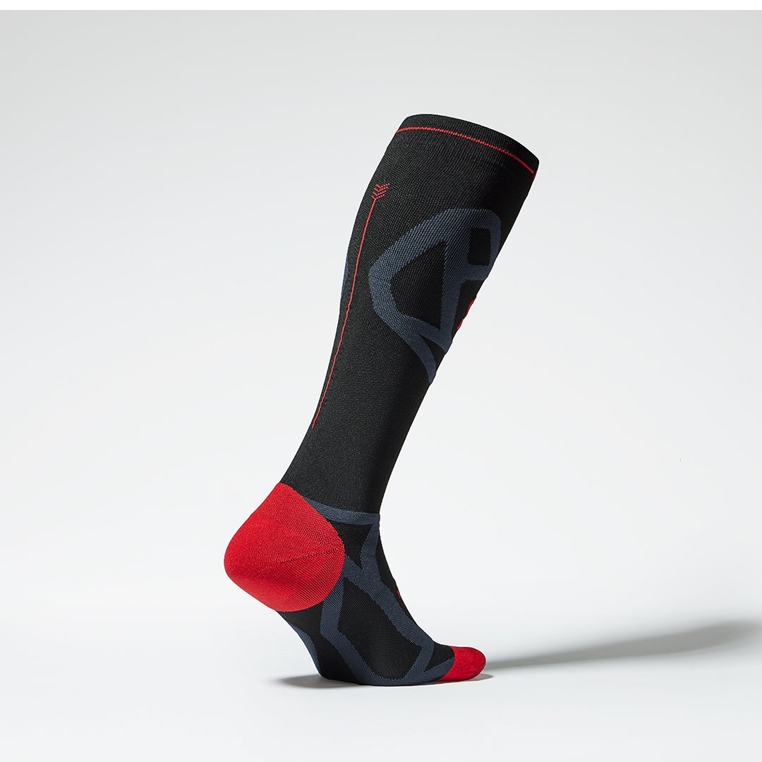 Side view of a knee high compression sock with red and anthracite grey details. 