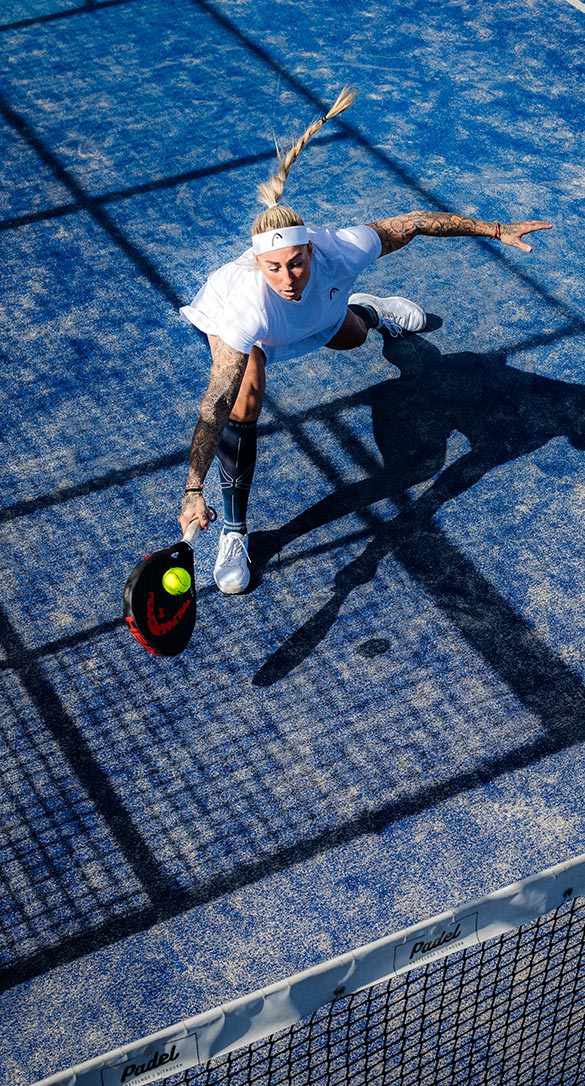 Women in action playing padel on a blue court.