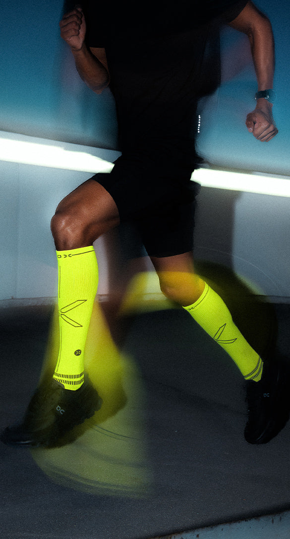 Man running in the dark with bright yellow high knee socks.