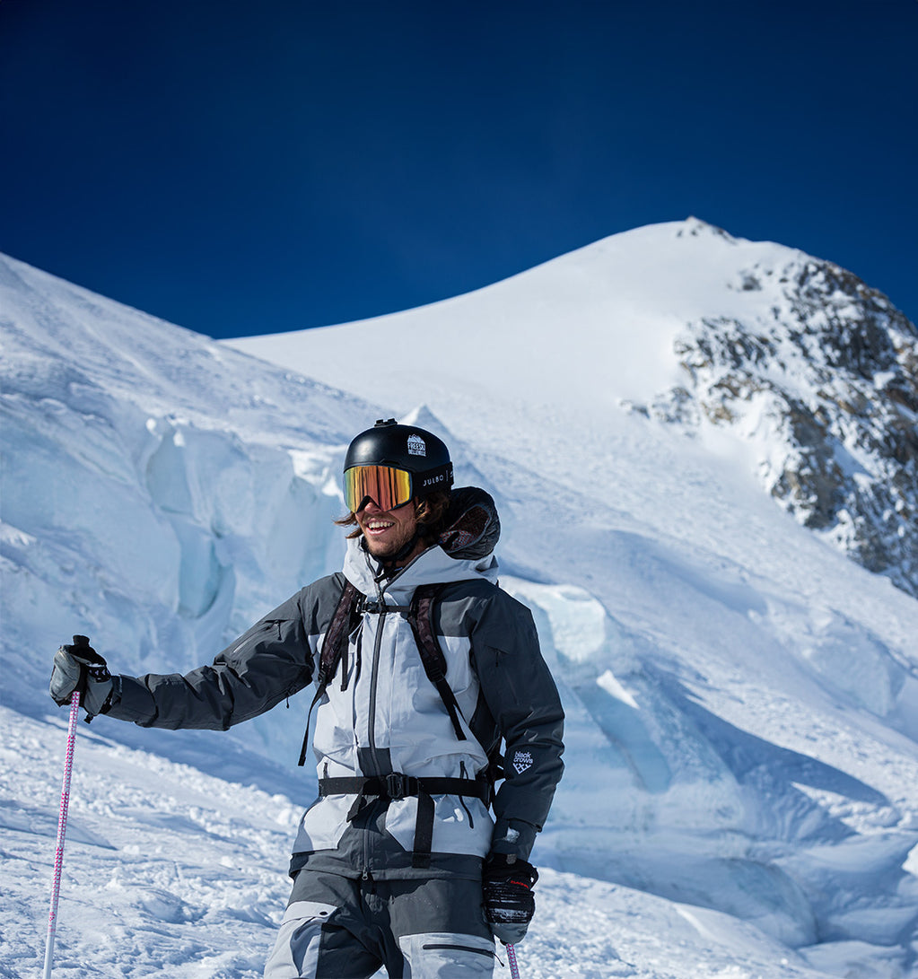 A skier is smiling while standing on a ski slope.