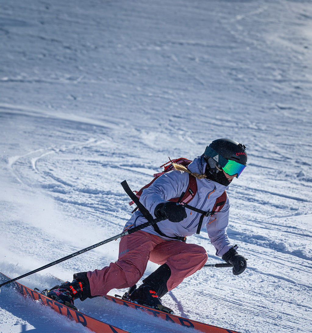 A skier is skiing wearing purple clothing.