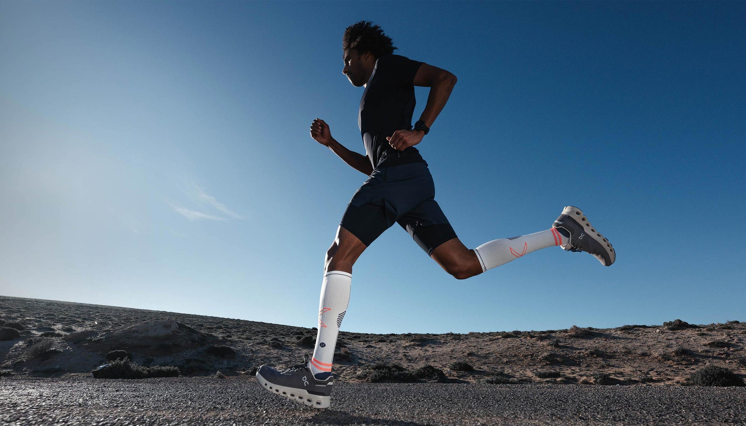 Person running on a rocky terrain with a clear blue sky