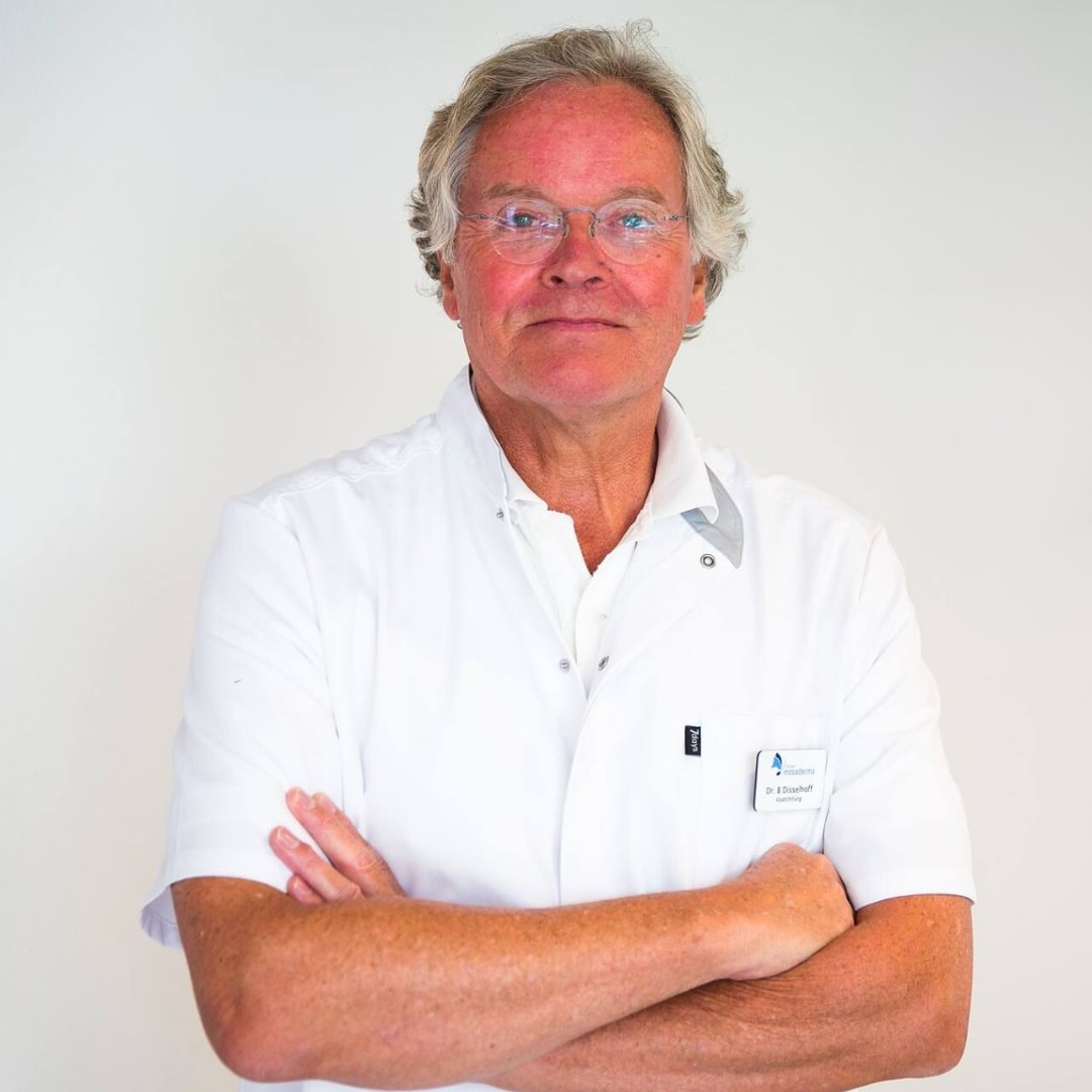 Man wearing white doctor's coat with his arms folded over each other.