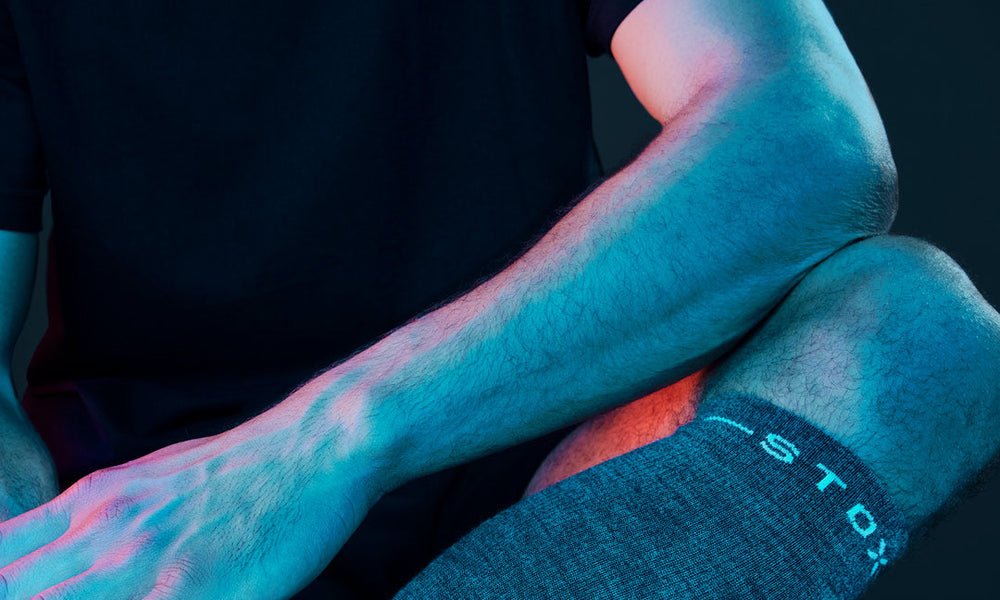 Sitting man in black room with compression socks.