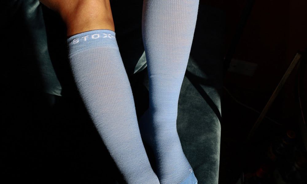 Woman sitting on couch with compression socks and coffee.