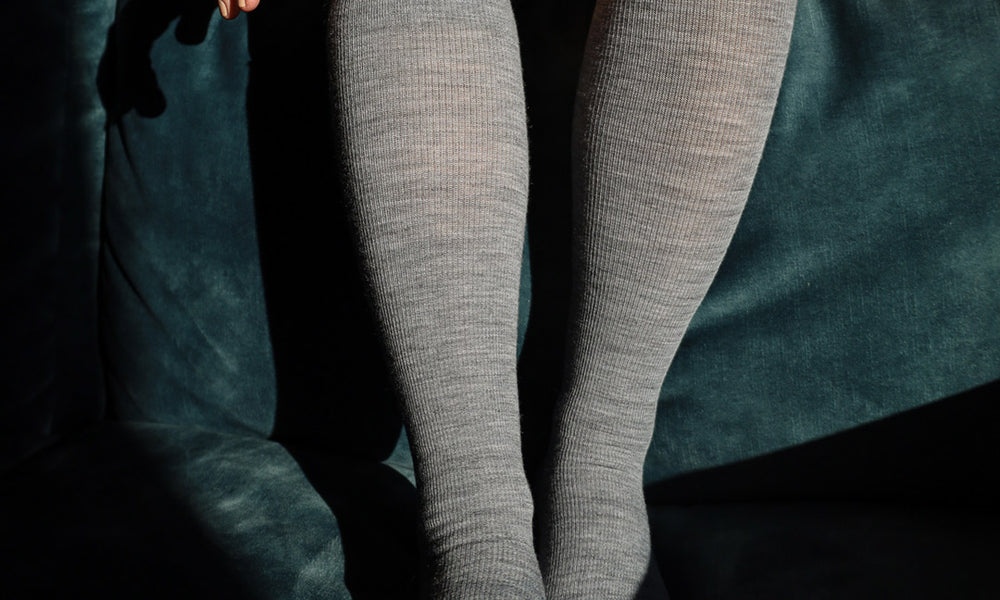 Woman sitting on couch with compression socks.