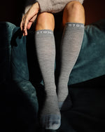 Woman sitting on couch with compression socks.