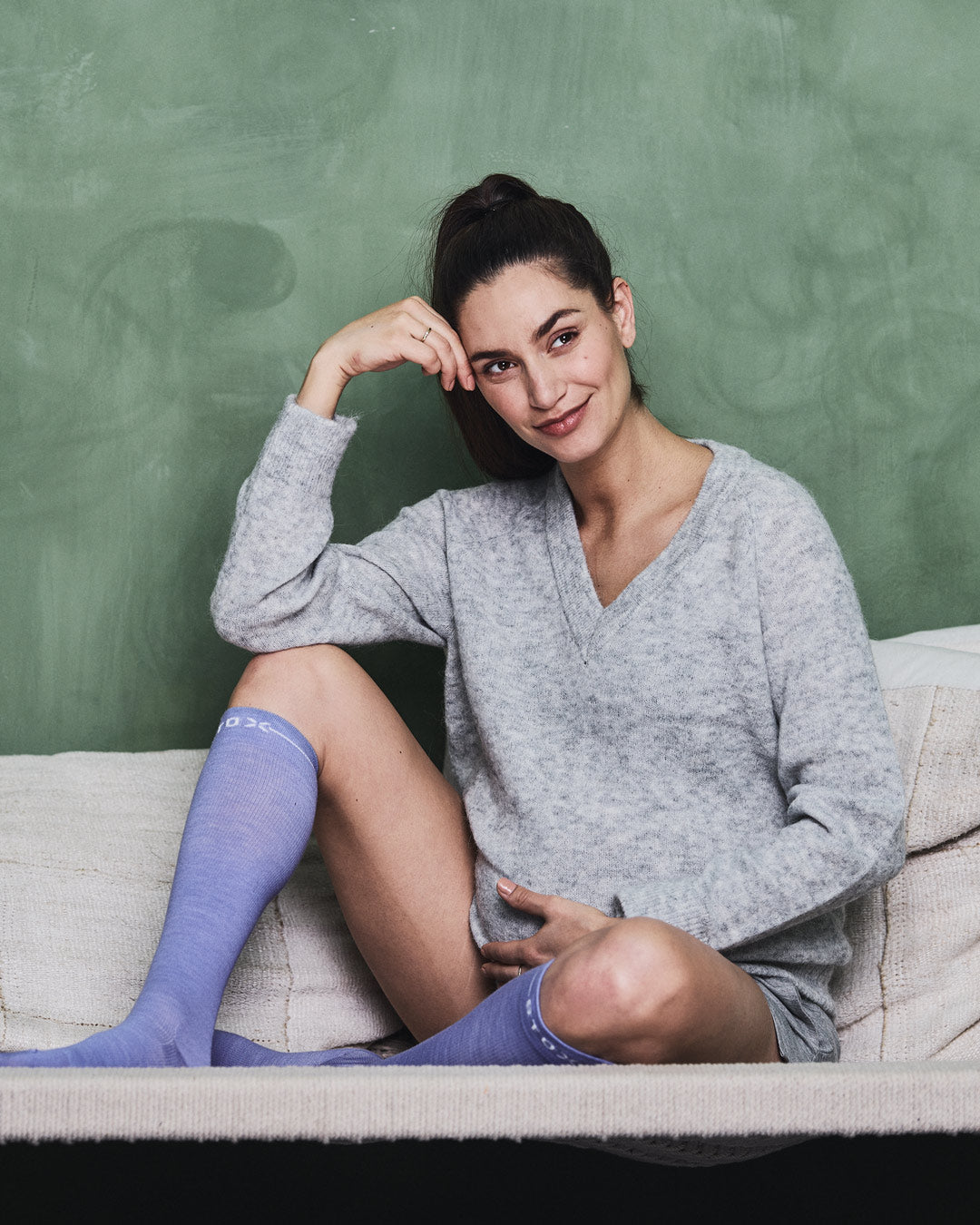 Pregnant woman sitting on a couch with compression socks.