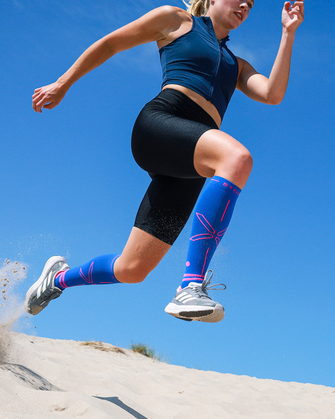Sprinting woman on sand with compression socks.