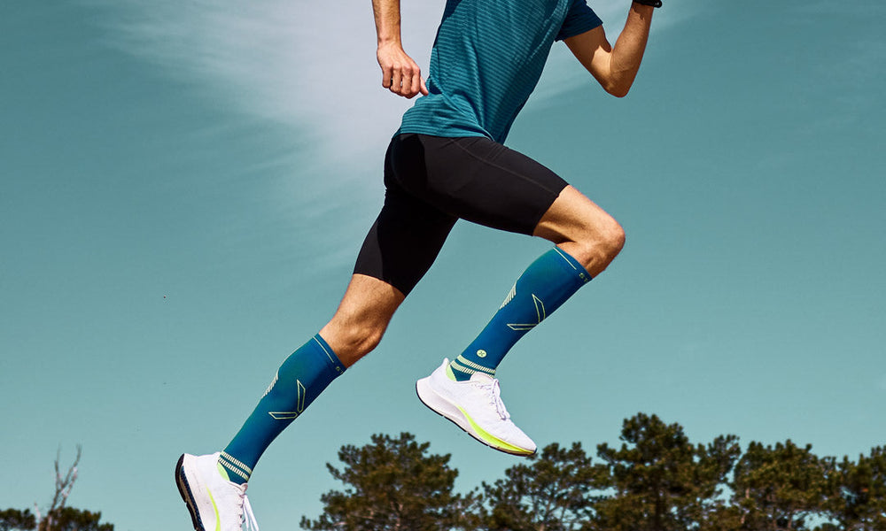 Men running on sand with compression socks.