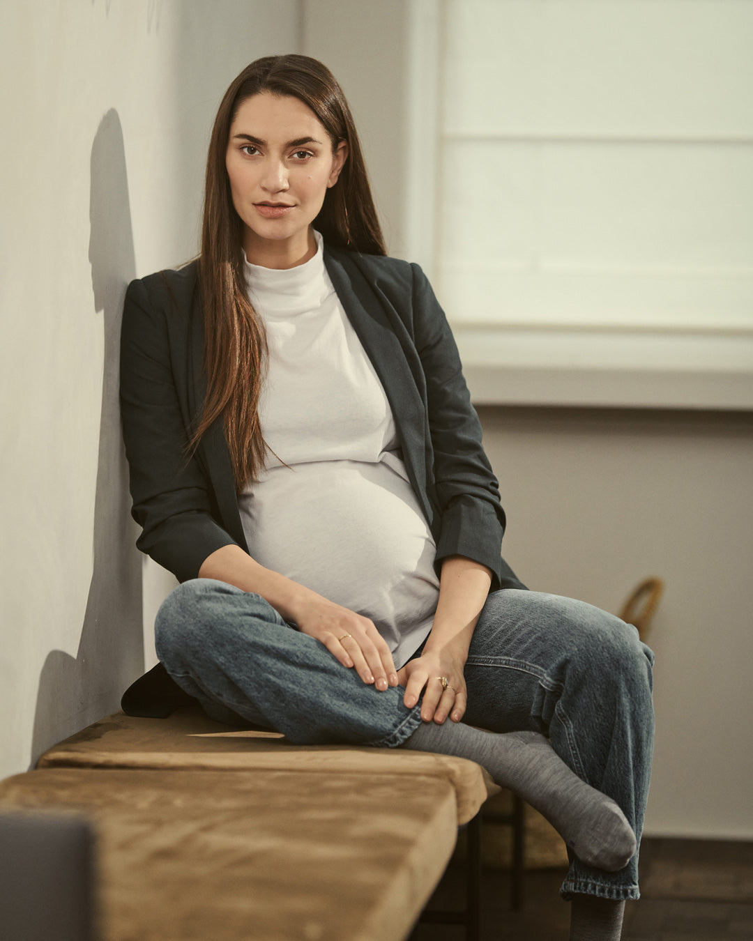 Pregnant woman sitting on a table with compression socks.
