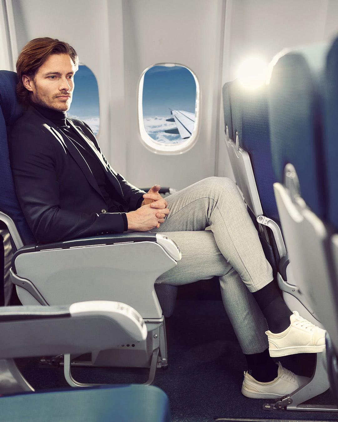 Men sitting in a airplane with compression socks.