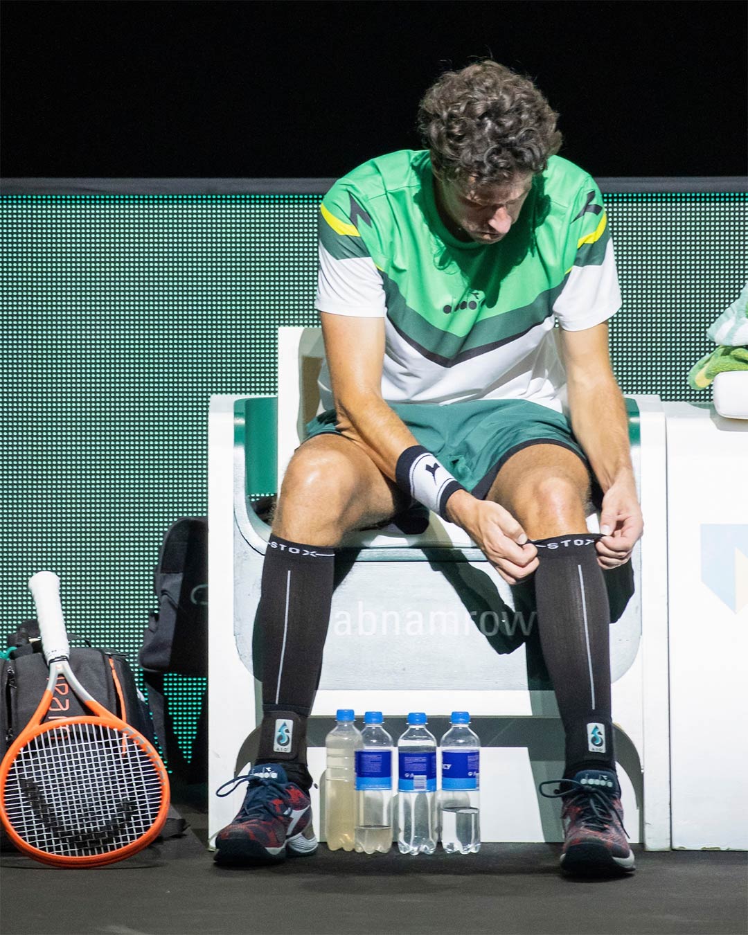 Robin Haase sitting courtside and pulling up his sock.