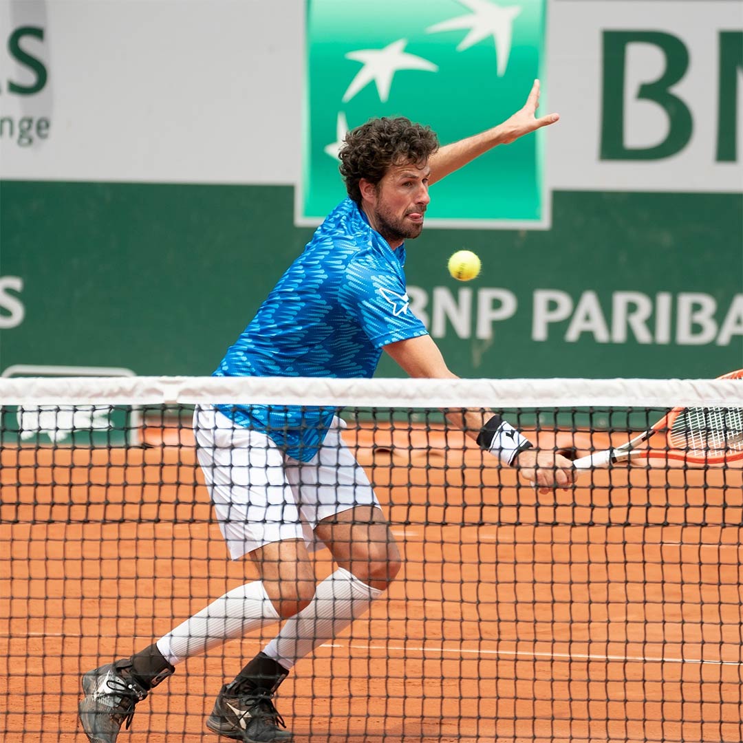 Robin Haase on a gravel court and holding an orange racket.