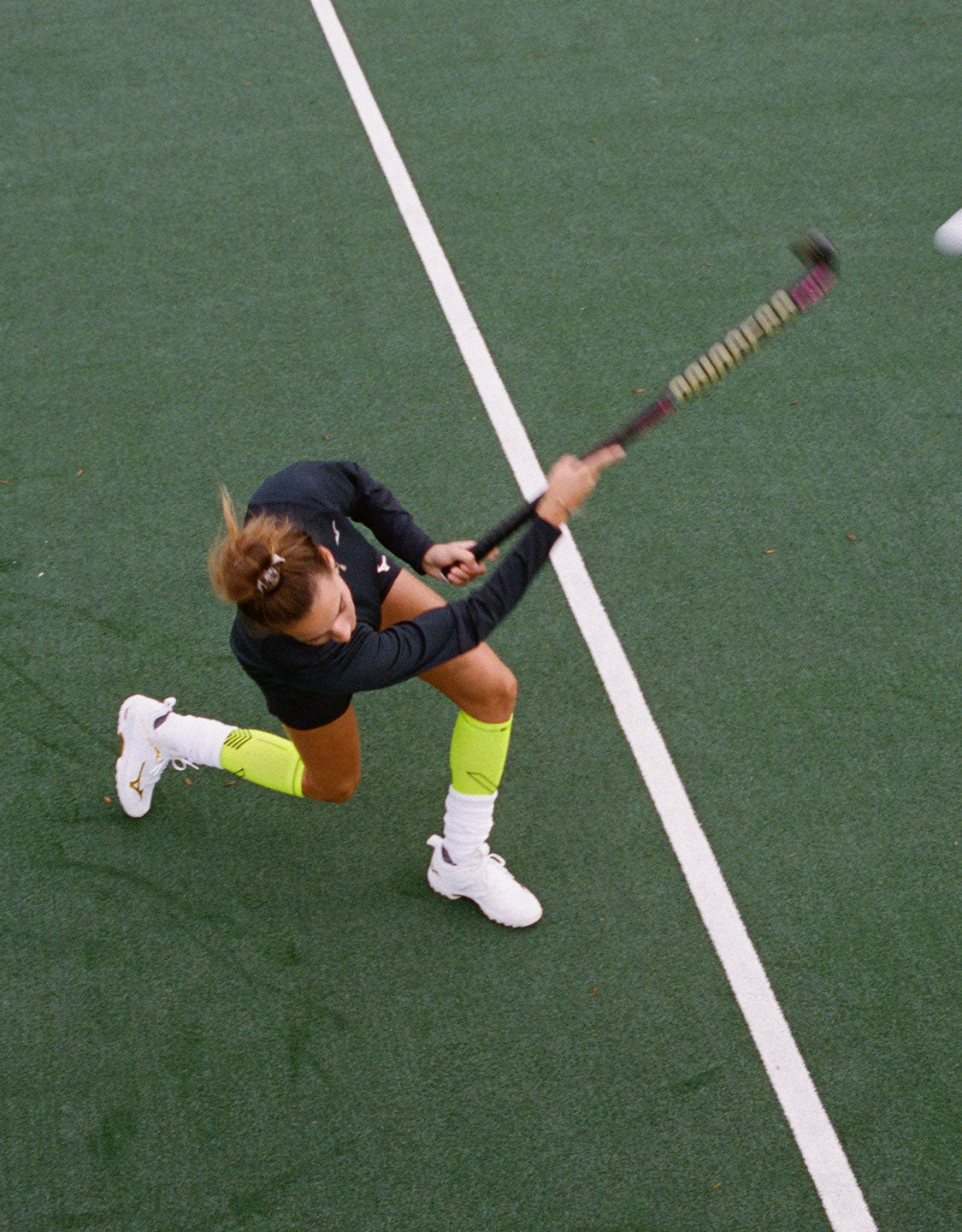 Field hockey player on field in action seen from above.