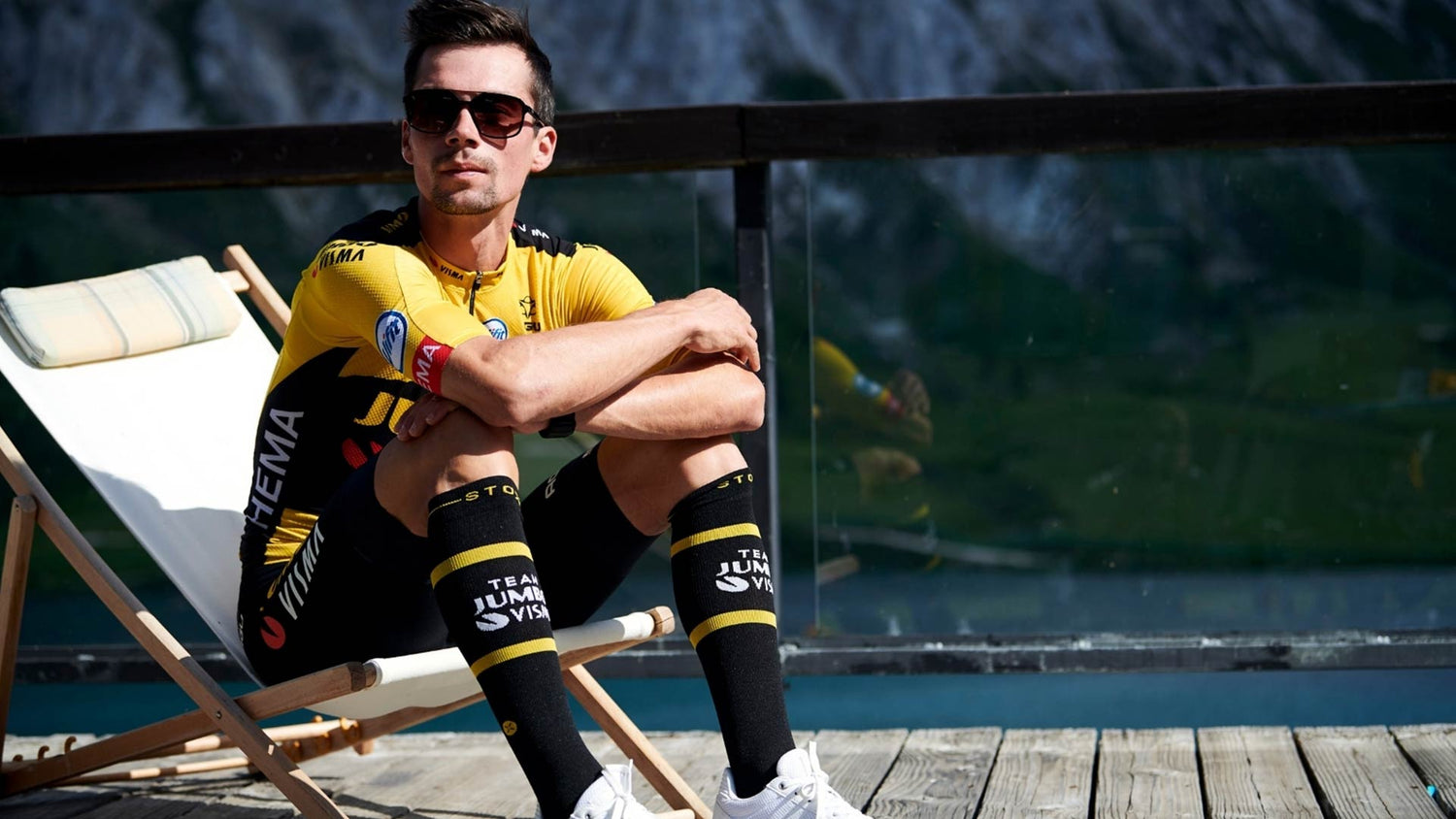 Primoz Roglic wearing sunglasses while sitting on a chair.