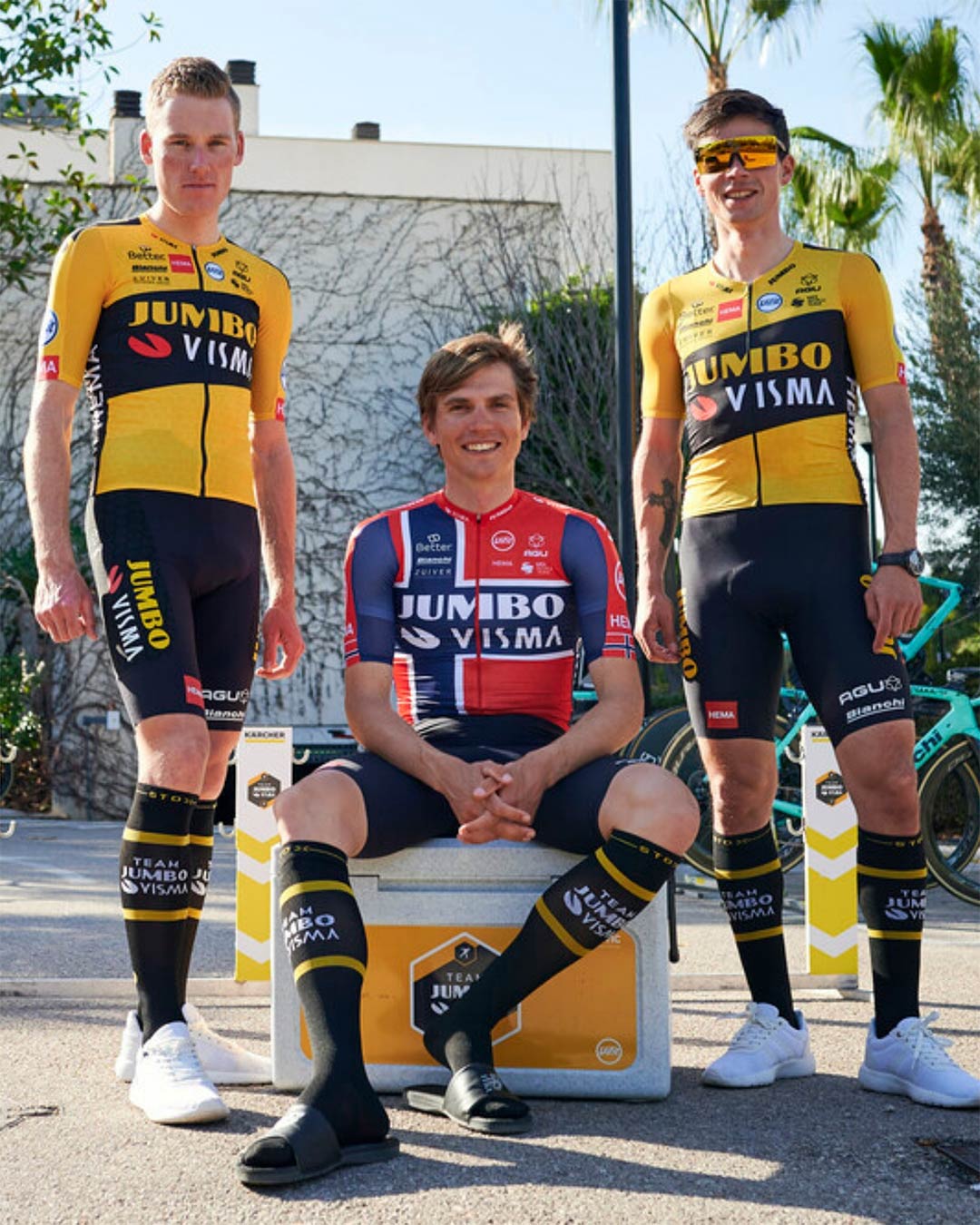Primoz Roglic posing with two other men on the street. 