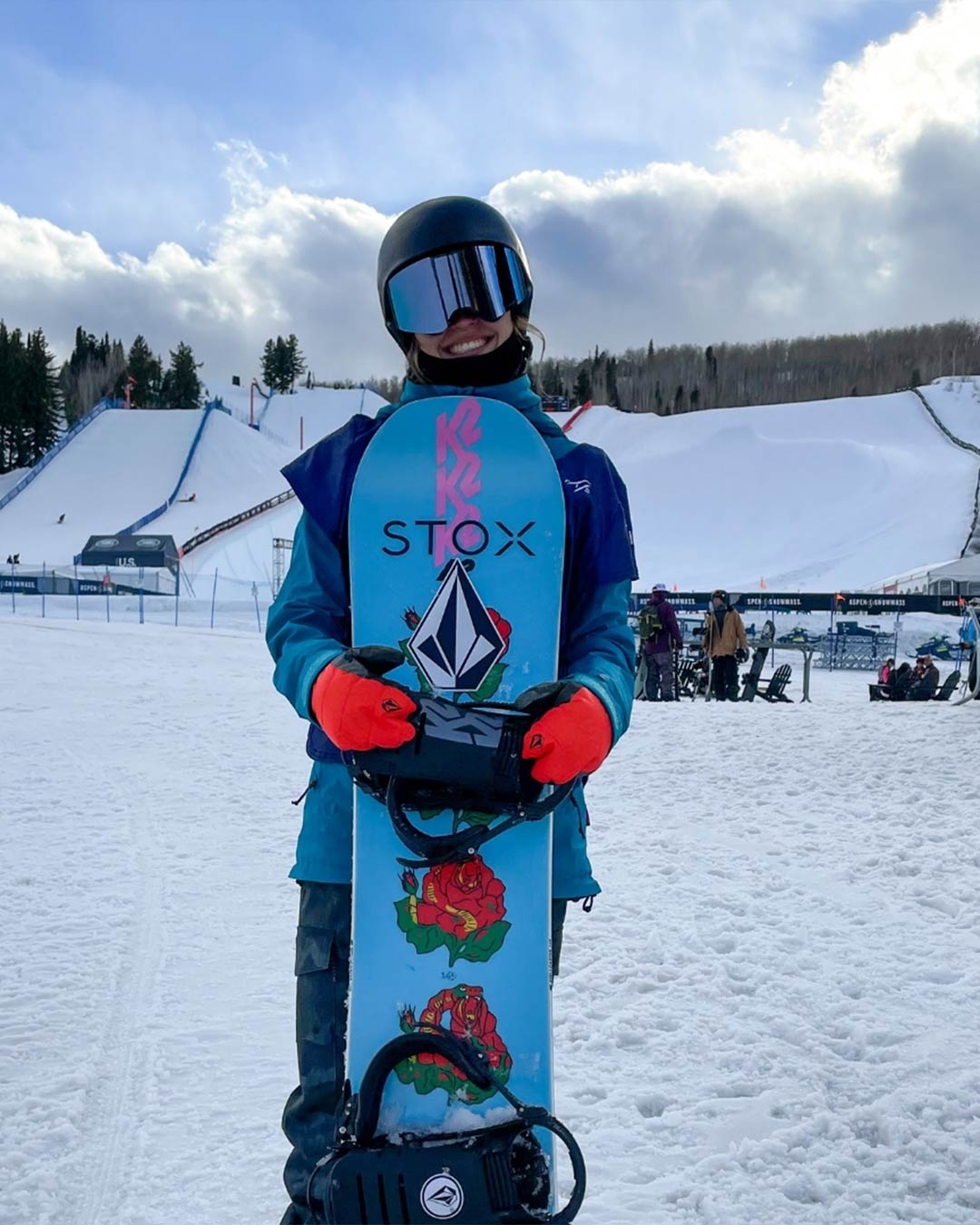 Loranne Smans holding a blue snowboard with roses printed on it. 