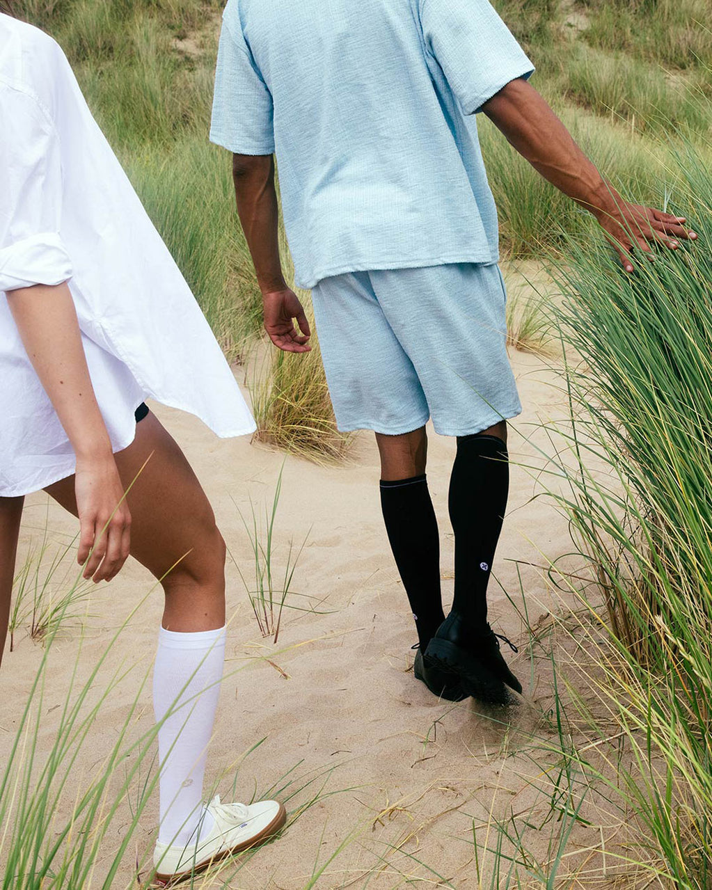 Couple walking in the dunes with long socks.