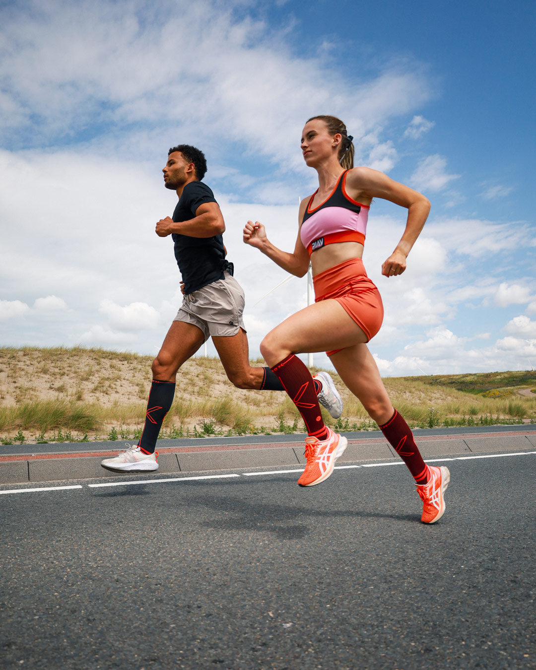 Man and woman running side by side in gray and red shorts