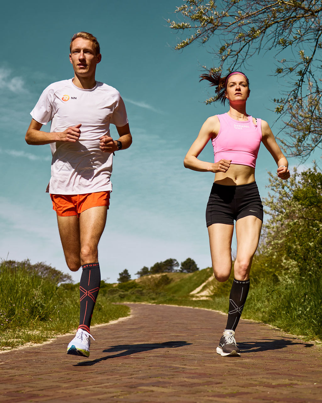 Bjorn Koreman and Jill Holterman running side by side in orange and black running shorts 