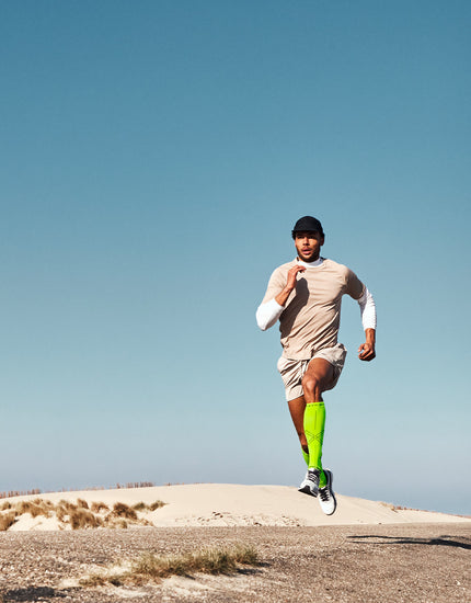 A man runs outside with a blue sky.